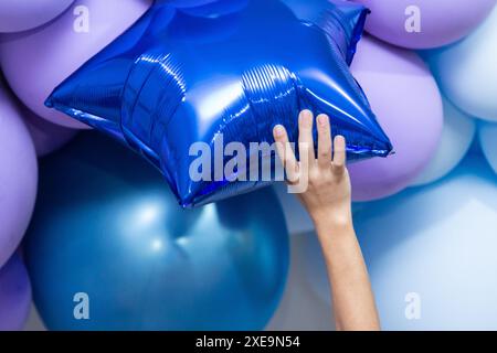 GOIANIA GOIAS BRÉSIL – JUIN 25 2024 : détail d'une main d'enfant attrapant un ballon bleu en forme d'étoile. Banque D'Images