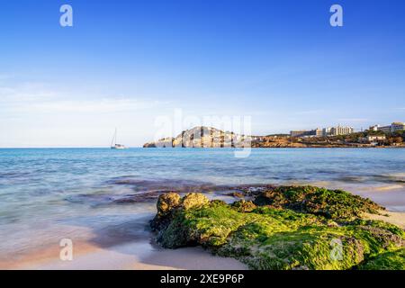 Vue sur la baie idyllique et la plage de Cala Agulla dans l'est de Majorque avec un voilier au premier plan Banque D'Images