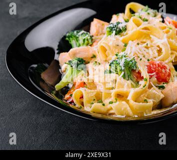 Plat italien de pâtes fettuccine alfredo avec saumon grillé et brocoli Banque D'Images