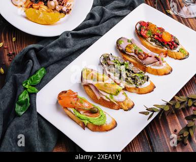 Bruschettas avec divers remplissages sur plaque blanche Banque D'Images