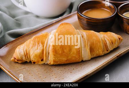 Croissants français frais avec chocolat sur assiette, miel et thé Banque D'Images