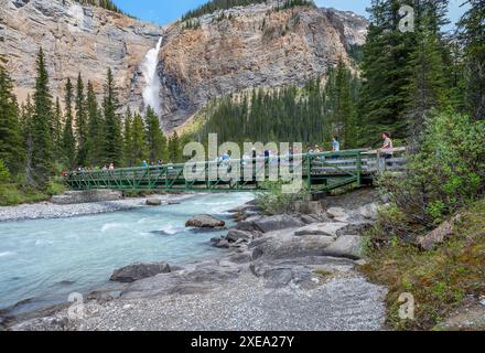 Parc national Yoho, Colombie-Britannique, Canada – 23 juin 2024 : les gens traversent un pont piétonnier sur la rivière Yoho à Takakkaw Falls Banque D'Images