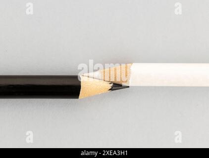 Crayon noir et crayon blanc se touchant ensemble sur fond gris. Concept d'Union de différentes cultures ou ethnies Banque D'Images
