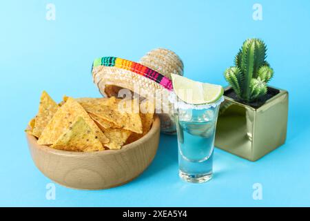 Chapeau de sombrero mexicain, cactus, chips de nachos et tequila sur fond bleu clair Banque D'Images