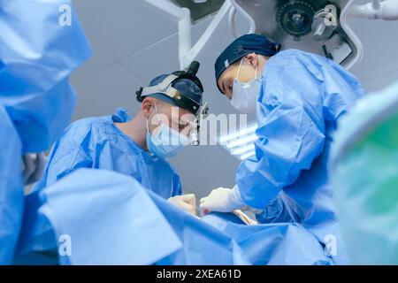 Les chirurgiens masculins effectuent la chirurgie dans la salle d'opération, chirurgien plastique dans la salle d'opération, Une équipe chirurgicale effectue une opération Banque D'Images