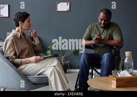 Portrait d'un homme noir adulte en tant que vétéran de l'armée handicapé partageant des luttes de santé mentale avec une psychologue féminine Banque D'Images