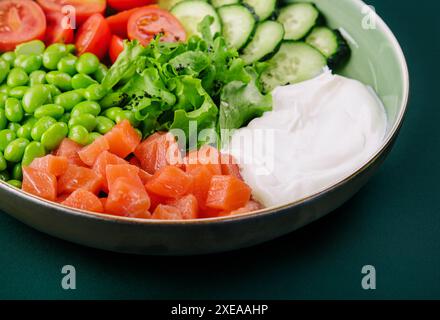 Poke bol avec saumon, concombre, tomate, riz et haricots edamame Banque D'Images