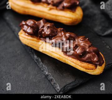 Deux eclairs avec du chocolat noir sur tableau noir Banque D'Images