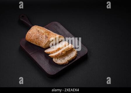 Baguette croustillante à la farine de blé avec des graines de sésame sur une planche à découper en bois Banque D'Images