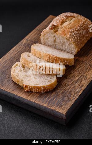 Baguette croustillante à la farine de blé avec des graines de sésame sur une planche à découper en bois Banque D'Images