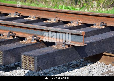 Nouvelle section de chemin de fer prête pour l'installation. Nouvelles attaches en bois recouvertes de créosote. Voies ferrées rouillées. Banque D'Images