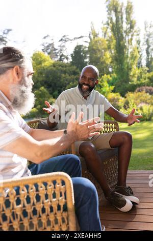 Parler et faire des gestes, amis seniors appréciant la conversation sur le patio extérieur Banque D'Images