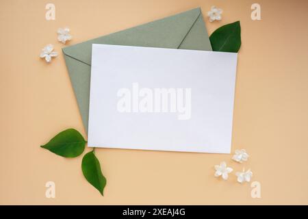 Composition avec enveloppe vide et belles fleurs de lilas de printemps sur fond beige. Maquette carte invitation carte de voeux pos Banque D'Images