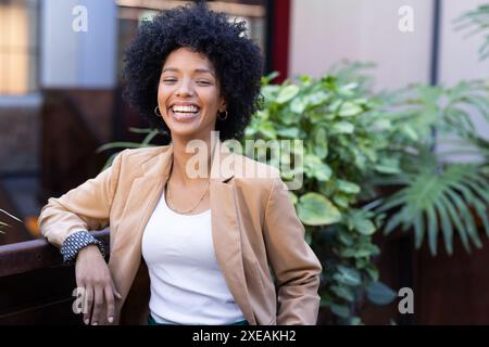 Femme d'affaires souriante en tenue décontractée debout à l'extérieur, appuyée sur la rampe Banque D'Images