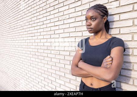 Jeune femme déterminée appuyée sur un mur de briques Banque D'Images