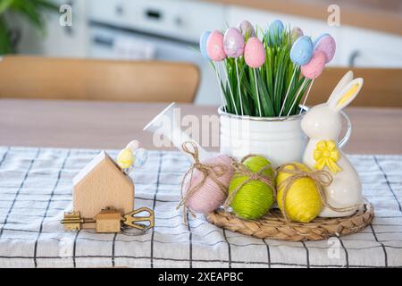 Clé et minuscule maison de maison confortable avec décor de Pâques avec lapin et oeufs sur la table de la cuisine. Construction, conception, projet, déménagement Banque D'Images