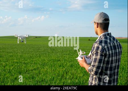 Technologies modernes en agriculture. Agriculteur pilotant un drone au-dessus d'un jeune champ de blé. Banque D'Images