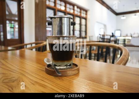 Goutte à goutte vietnamienne, café vietnamien au lait condensé dans des tasses en verre et cafetière traditionnelle en métal phin. Méthode traditionnelle de fabrication du vietname Banque D'Images