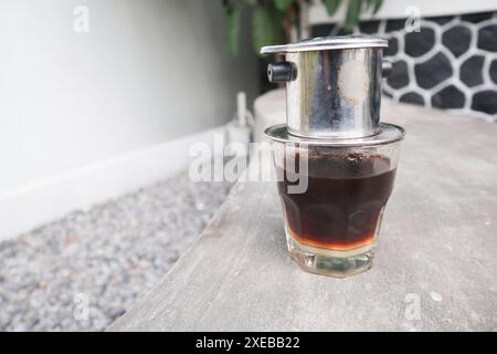 Goutte à goutte vietnamienne, café vietnamien au lait condensé dans des tasses en verre et cafetière traditionnelle en métal phin. Méthode traditionnelle de fabrication du vietname Banque D'Images