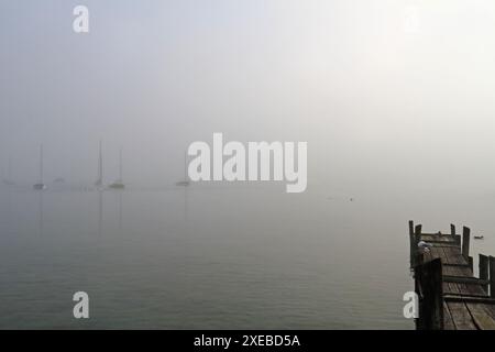 Quelques voiliers en contre-jour sur le lac Ammersee dans la brume matinale Banque D'Images