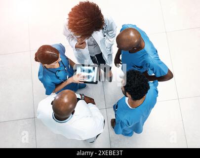 Vue de dessus, écran de tablette et médecins dans le hall, radiographie ou travail d'équipe pour le retour d'information de la chirurgie. Spécialiste, médical ou professionnel avec technologie, conseil ou Banque D'Images