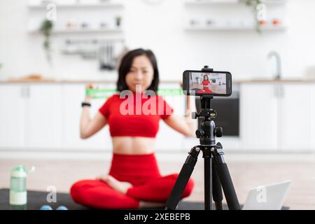Femme enregistrant la vidéo de fitness dans la configuration de la cuisine à domicile Banque D'Images