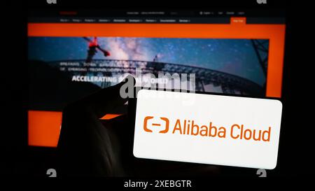 Personne tenant un smartphone avec le logo de la société informatique chinoise Alibaba Cloud en face du site Web. Concentrez-vous sur l'affichage du téléphone. Banque D'Images