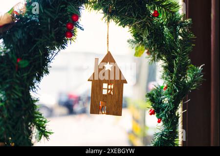 Maison de jouet en bois accroché sur la guirlande d'arbre de noël à la porte en fête de noël Banque D'Images