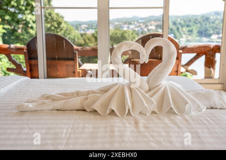 Serviettes pliées en forme de cygne de couple sur le lit de l'hôtel Banque D'Images