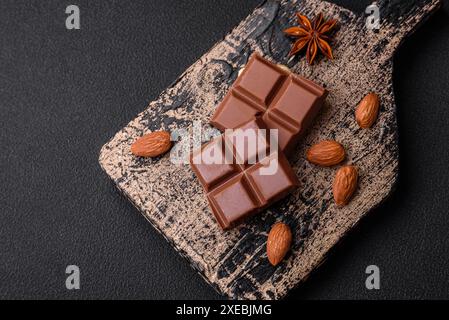 Délicieux chocolat au lait sucré cassé en cubes sur une planche à découper en bois Banque D'Images