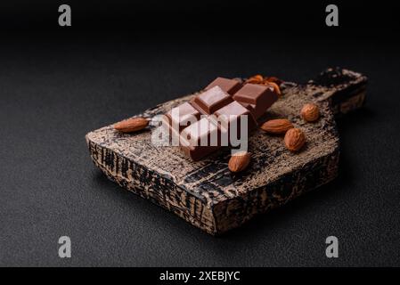 Délicieux chocolat au lait sucré cassé en cubes sur une planche à découper en bois Banque D'Images