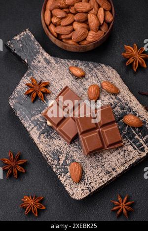 Délicieux chocolat au lait sucré cassé en cubes sur une planche à découper en bois Banque D'Images