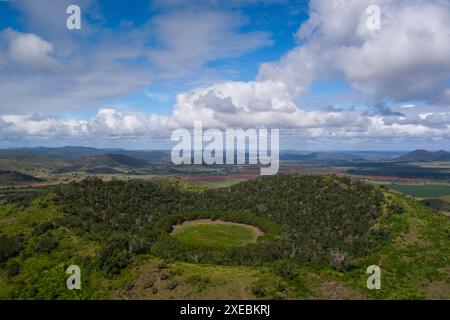 Vue aérienne d'un cratère volcanique vert luxuriant avec la forêt environnante et les terres agricoles en arrière-plan Banque D'Images