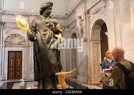 Amsterdam, pays-Bas. 26 juin 2024. Un visiteur prend une photo d'une statue de bronze lors de l'avant-première de presse pour l'exposition 'look Up! Un toit plein d'histoires à raconter' au Palais Royal d'Amsterdam, pays-Bas, le 26 juin 2024. L’exposition sera ouverte au public du 29 juin au 22 septembre, offrant aux visiteurs la possibilité de regarder de plus près les œuvres d’art qui se trouvent normalement sur le toit du palais. Crédit : Sylvia Lederer/Xinhua/Alamy Live News Banque D'Images