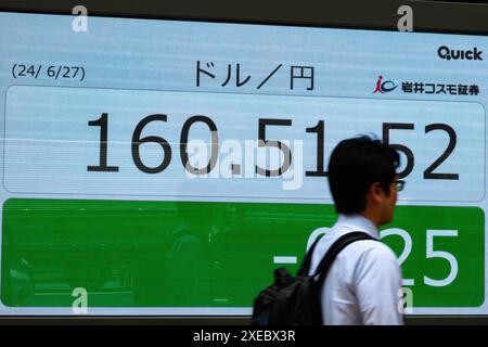 Tokyo, Japon. 27 juin 2024. Un homme passe devant un écran électronique montrant le taux de change en temps réel du yen japonais contre le dollar américain à Tokyo, Japon, le 27 juin 2024. Le dollar américain a grimpé jusqu'à 160,88 yens à New York, marquant le niveau le plus faible de la monnaie japonaise depuis décembre 1986 et dépassant les 160,24 yens frappés le 29 avril, un niveau qui a incité le Japon à intervenir en achetant le yen contre la monnaie américaine. Crédit : Zhang Xiaoyu/Xinhua/Alamy Live News Banque D'Images