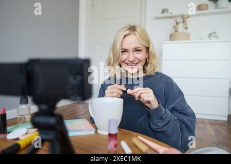 Portrait de femme souriante blonde enregistre un blog de style de vie, vlogger ou maquilleur enregistrant une vidéo pour les médias sociaux, tenant mas Banque D'Images