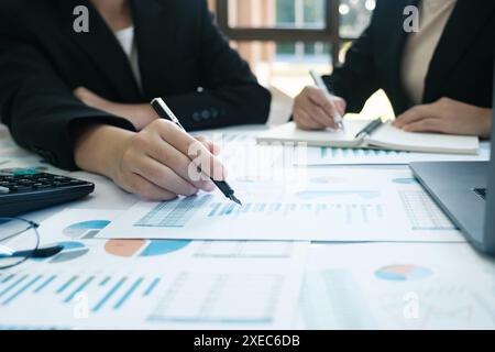 Deux personnes sont assises à une table avec beaucoup de papiers et un ordinateur portable Banque D'Images