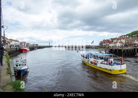 Bateau de croisière de plaisance se dirige dans la mer du Nord depuis le port de Whitby chargé de holdiaymakers profitant de leurs vacances bancaires avec une staycation au Royaume-Uni Banque D'Images