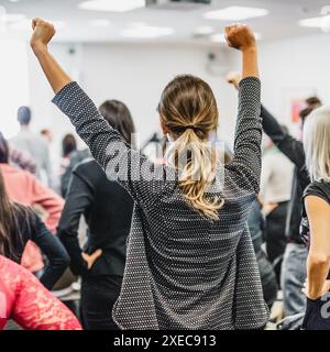 Symposium de coaching de vie. Conférencier donnant un discours de motivation interactif à l'atelier d'affaires. Vue arrière des participants méconnaissables se sentant autonomes et motivés, les mains levées en l'air. Banque D'Images