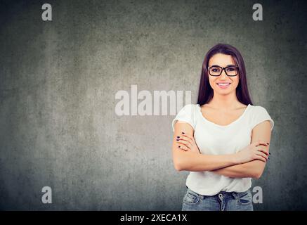 Femme heureuse debout dans une tenue décontractée, souriant heureux à la caméra et regardant confiant Banque D'Images