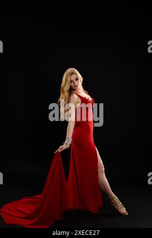 Une femme gracieuse dans une robe rouge éclatante frappe une pose. Banque D'Images