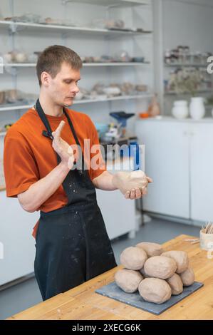 Potter pétrit l'argile avant de l'utiliser dans l'atelier. Photo verticale. Banque D'Images