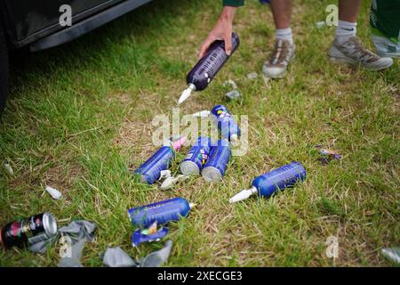 Un membre de l'équipe de nettoyage de Glastonbury nettoyant des cartouches d'oxyde nitreux jetées dans un parking, au festival de Glastonbury à Worthy Farm dans le Somerset. Date de la photo : jeudi 27 juin 2024. Banque D'Images