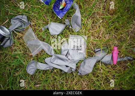 Ballons jetés laissés à côté des cartouches d'oxyde nitreux dans un parking, au festival de Glastonbury à Worthy Farm dans le Somerset. Date de la photo : jeudi 27 juin 2024. Banque D'Images