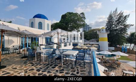 Salle à manger extérieure relaxante avec tables ombragées et parasols colorés sur fond de verdure luxuriante et bleu clair SK Banque D'Images