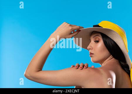 Un adolescent dans un grand chapeau de plage tient une main sur une épaule bronzée. Banque D'Images