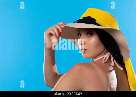 Un adolescent dans un grand chapeau de plage tient une main sur une épaule bronzée. Banque D'Images