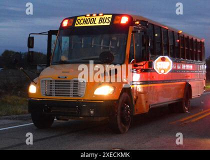 WASHINGTON (7 avril 2020) ¬ — vue après l'accident d'un autobus scolaire impliqué dans l'accident du 30 octobre 2018, Rochester, Indiana, impliquant quatre élèves qui traversaient une route à grande vitesse pour monter à bord d'un autobus scolaire. La photo prise le 30 octobre 2018 est l'autobus scolaire construit par Thomas dans des conditions de faible luminosité dans sa position sur la SR-25 en direction nord au moment de l'accident. Les phares avant et les feux d’avertissement rouges de l’autobus sont actifs, et le bras d’arrêt s’étend du côté gauche de l’autobus, derrière et sous la vitre du conducteur. (Photo de la police d'État de l'Indiana) WASHINGTON (7 avril 2020) ¬— vue de l'école après l'accident b Banque D'Images