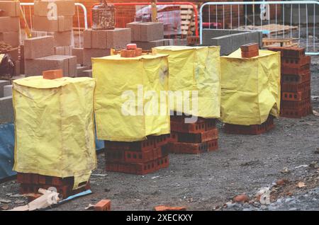 Briques rouges et blocs de béton livrés sur le chantier et placés à côté du lieu de travail prêt pour les briques Banque D'Images