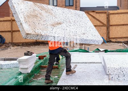 Constructeur plaçant des panneaux isolants de polystyrène sur la membrane d'étanchéité pendant la construction de plancher. Concept d'économie d'énergie Banque D'Images